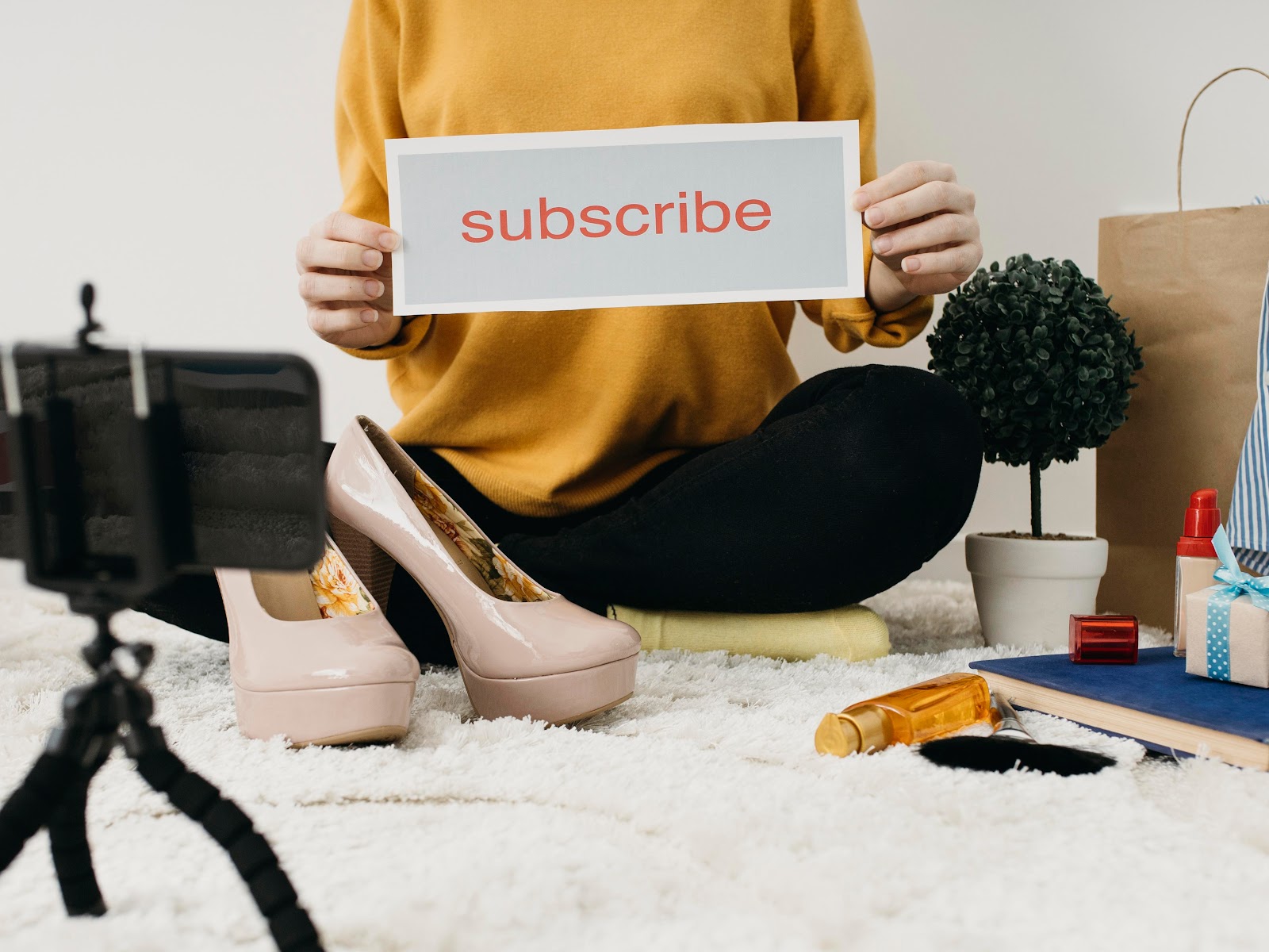 Female fashion blogger streaming at home with smartphone and subscribe word